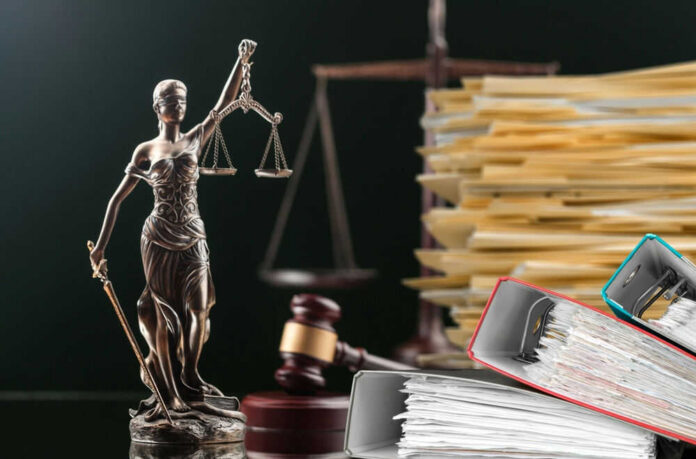 Lady Justice statue beside gavel and stacks of legal files