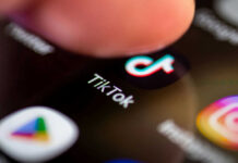 FIRED After Viral TikTok Targeting Pam Bondi Sparks Backlash Finger tapping TikTok app on a smartphone screen