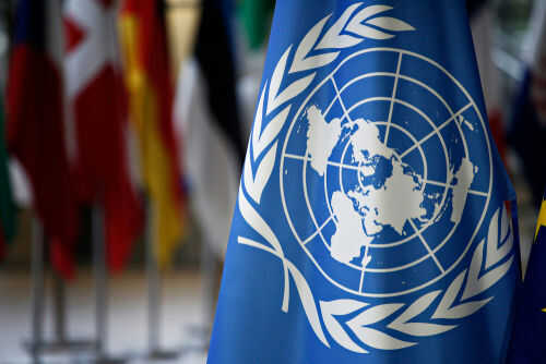 united-nation-un1091235845 United Nations flag with world map emblem displayed
