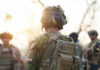 Soldier in camouflage gear with helmet and radio backpack