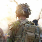 Soldier in camouflage gear with helmet and radio backpack