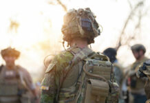 Soldier in camouflage gear with helmet and radio backpack