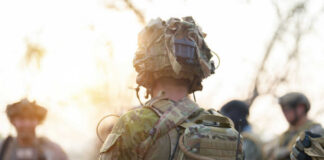 Soldier in camouflage gear with helmet and radio backpack