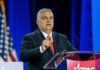 Man in suit speaking at a podium on a stage