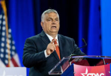 Man in suit speaking at a podium on a stage
