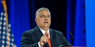 Man in suit speaking at a podium on a stage