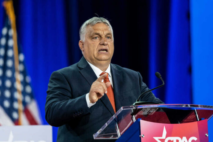 Man in suit speaking at a podium on a stage