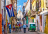 Socialism Crashes — Cuba Scrambles For Cash Colorful street scene with Cuban flag and people.