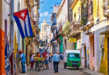 Socialism Crashes — Cuba Scrambles For Cash Colorful street scene with Cuban flag and people.