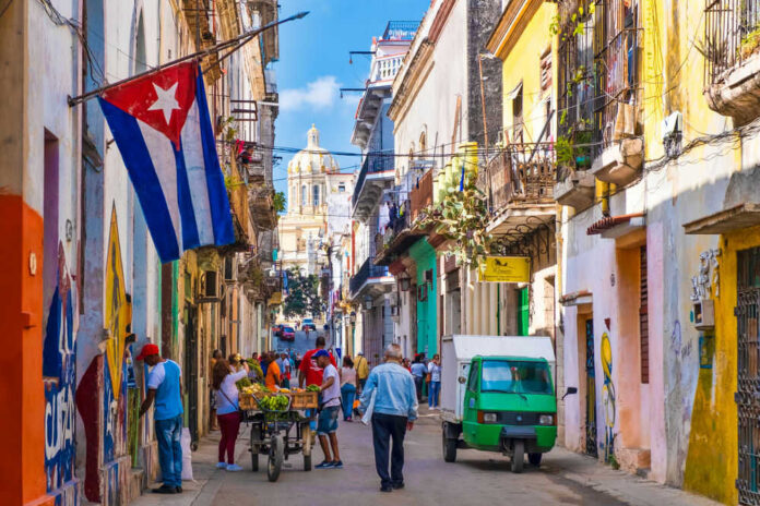 239424732 Colorful street scene with Cuban flag and people.
