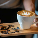 Public Shaming Backfires — Civil Rights Heat Latte with latte art on a wooden tray with coffee beans and a spoon