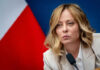 Person speaking at a conference with flag background