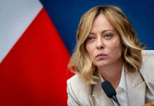 Diplomatic Meltdown Over One Photo Person speaking at a conference with flag background