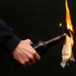 Mobs Torch Homes After Shocking Stabbing Person holding molotov cocktail with flame burning cloth