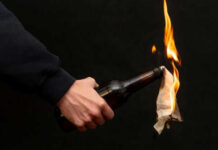 Mobs Torch Homes After Shocking Stabbing Person holding molotov cocktail with flame burning cloth
