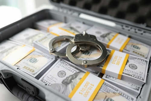 money-arrest2272522819 Briefcase with handcuffs and stacks of US dollars
