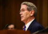 Bessent Hits Back: Wyden’s Son Pitched Epstein Man in suit speaking at a microphone indoors