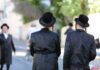 NYC Antisemitic Hate Crimes Spike — One Every 18 Hours Two men in traditional black attire and hats walking down a street