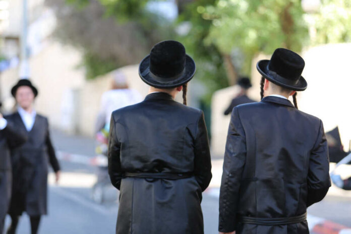 View,From,The,Back,Side,Of,Two,Ultra,Orthodox,Hasidic Two men in traditional black attire and hats walking down a street