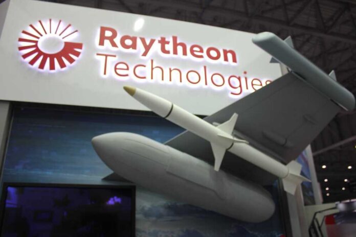 Dubai,,Uae,-,November,14,,2021:,Raytheon,Technologies,Exhibitor,Pavilion Two workers in hard hats and masks review a tablet in a factory