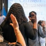 Denaturalization Campaign Expands—Fraud Cases Targeted Participants raising their hands during a citizenship oath ceremony