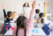 Holiday Purge Looms — Parents Furious Students in a classroom raising their hands to answer a question