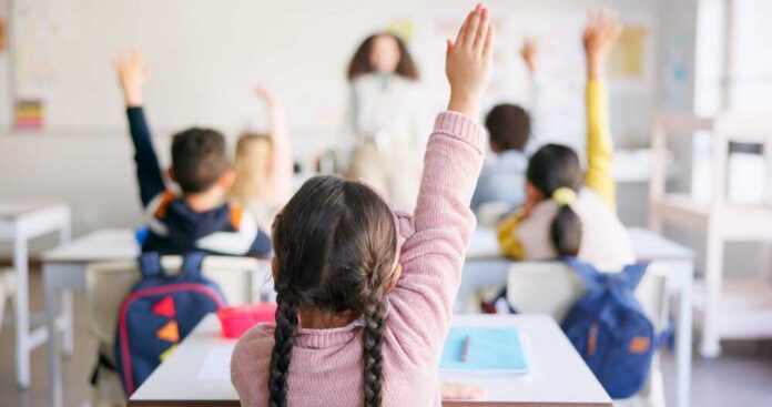 Learning,,Question,And,Hands,Raised,With,Girl,In,Classroom,For Students in a classroom raising their hands to answer a question