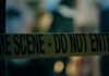 Portland Serial Allegations Grow — Fifth Murder Charge Filed Caution tape marking a crime scene with blurred figures in the background