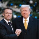Economic War Plans Quietly Advance Two political leaders shaking hands in front of a decorated backdrop