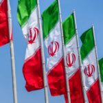 Coup Rumors Explode—Who Runs Iran Now? Multiple Iranian flags waving against a clear blue sky