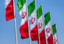 Coup Rumors Explode—Who Runs Iran Now? Multiple Iranian flags waving against a clear blue sky