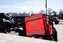 Minimum Wage Move Backfires—Orders Vanish A motorcycle with a bright red Doordash delivery bag parked in an urban area