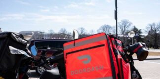 A motorcycle with a bright red Doordash delivery bag parked in an urban area