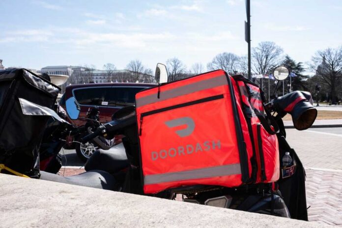 A motorcycle with a bright red Doordash delivery bag parked in an urban area