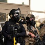 Police officers in tactical gear wear gas masks during a crowd control operation
