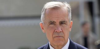 A man in formal attire with a serious expression outdoors