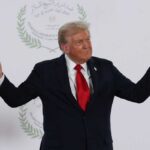A political figure gesturing with hands during a public appearance
