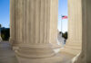 Birthright Shock: Justices Signal Turbulence Marble columns of a neoclassical building with U.S. flag in background