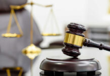 Billionaire Crusader Exposed As Mega Fraud A wooden gavel resting on a sound block with a blurred scale of justice in the background