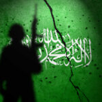 Silhouette of armed soldier before cracked green wall with white script