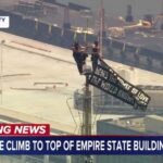 Two people climb to the top of Empire State Building spire, unfurl banner