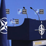 Spending Explosion: NATO Eyes 5% by 2035 NATO podium with flags and microphones.