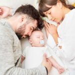 Parents sleeping beside newborn baby