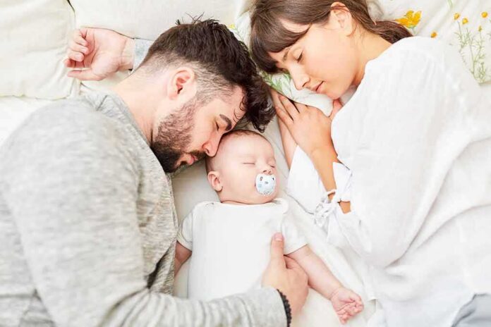 shutterstock_1247495608 Parents sleeping beside newborn baby