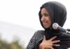 Omar’s ‘Benjamins’ Boomerang — Campaigns On Edge Woman in black hijab speaking at a microphone outdoors
