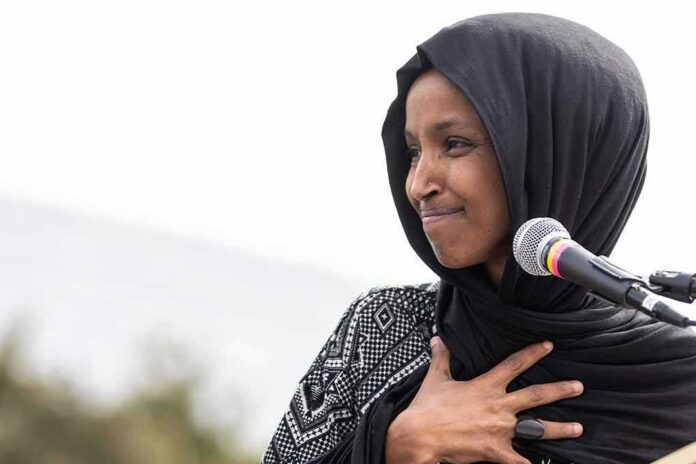 Woman in black hijab speaking at a microphone outdoors