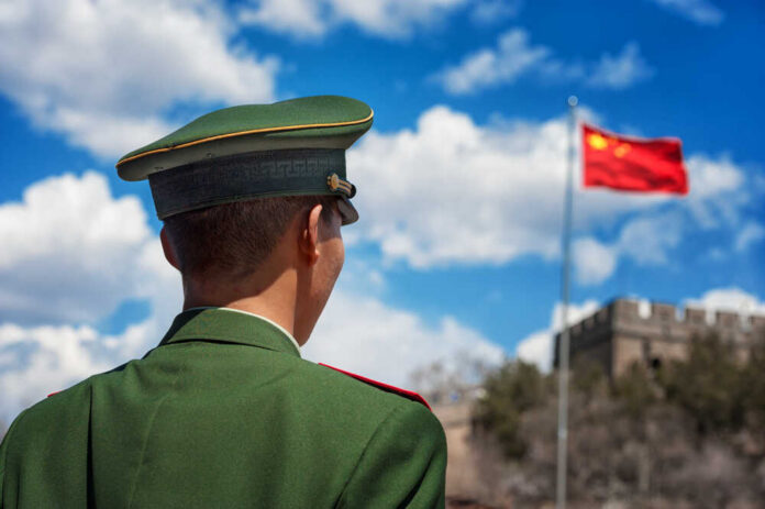 Beijing,-,April,24:,Soldier,Stands,Guard,Near,The,Great Soldier in a green military uniform facing the Great Wall of China with the Chinese flag in the background