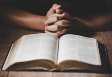28,551 Dead—But Not ‘Genocide’? Hands clasped over an open book on a wooden table