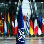 NATO flag with member country flags in the background