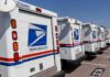 Row of USPS mail trucks parked in a lot